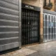 Tres escaparates en una calle de Barcelona muestran diferentes opciones de rejas de seguridad para un local comercial.