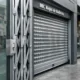 Entrada de tienda con reja de acordeón galvanizada y persiana enrollable perforada. Que tipos de rejas son mas adecuados para la proteccion de tiendas en areas urbanas